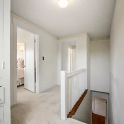 Upstairs hallway, with stairway visible. Carpet flooring is newer.